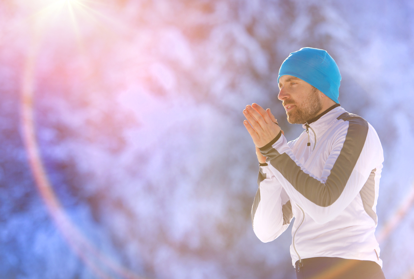 Young runner warms him up while resting during his training outside in sunny winter park