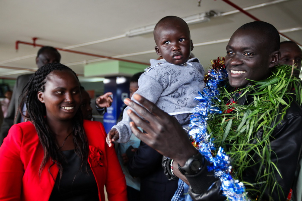 epa04425585 41st edition of the Berlin Marathon world record holder Dennis Kimetto (R) carries his son Alphine Kibet as his wife Caroline Kimetto (L) looks on after he was received by his family and friends upon arrival at the Jomo Kenyatta International Airport (JKIA) in Nairobi, Kenya, 01 October 2014. Kimetto bettered the marathon world record, clocking 2 hours, 2 minutes and 57 seconds. EPA/DANIEL IRUNGU Dostawca: PAP/EPA.