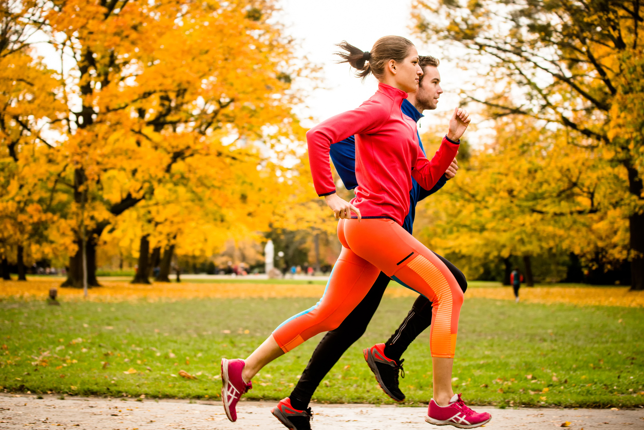 Young couple jogging together in park - rear view