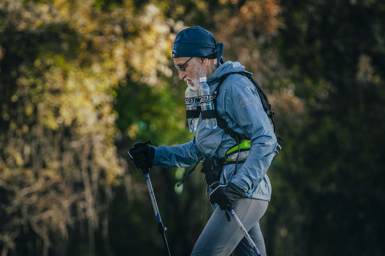 Yalta, Russia - October 31, 2015: old athlete is distance of race, with a backpack and water bottles during First Yalta mountain marathon