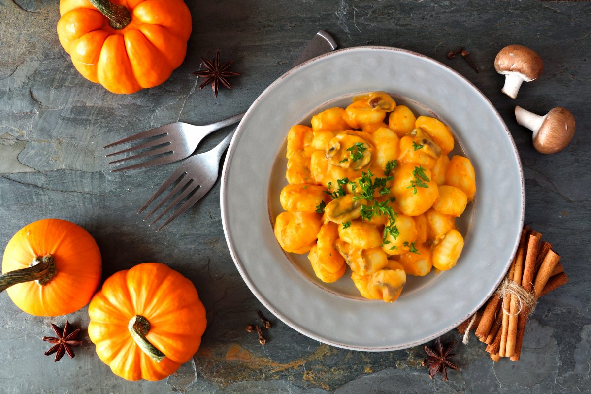 Gnocchi with a pumpkin, mushroom cream sauce. Autumn meal. Top view scene on a dark background.