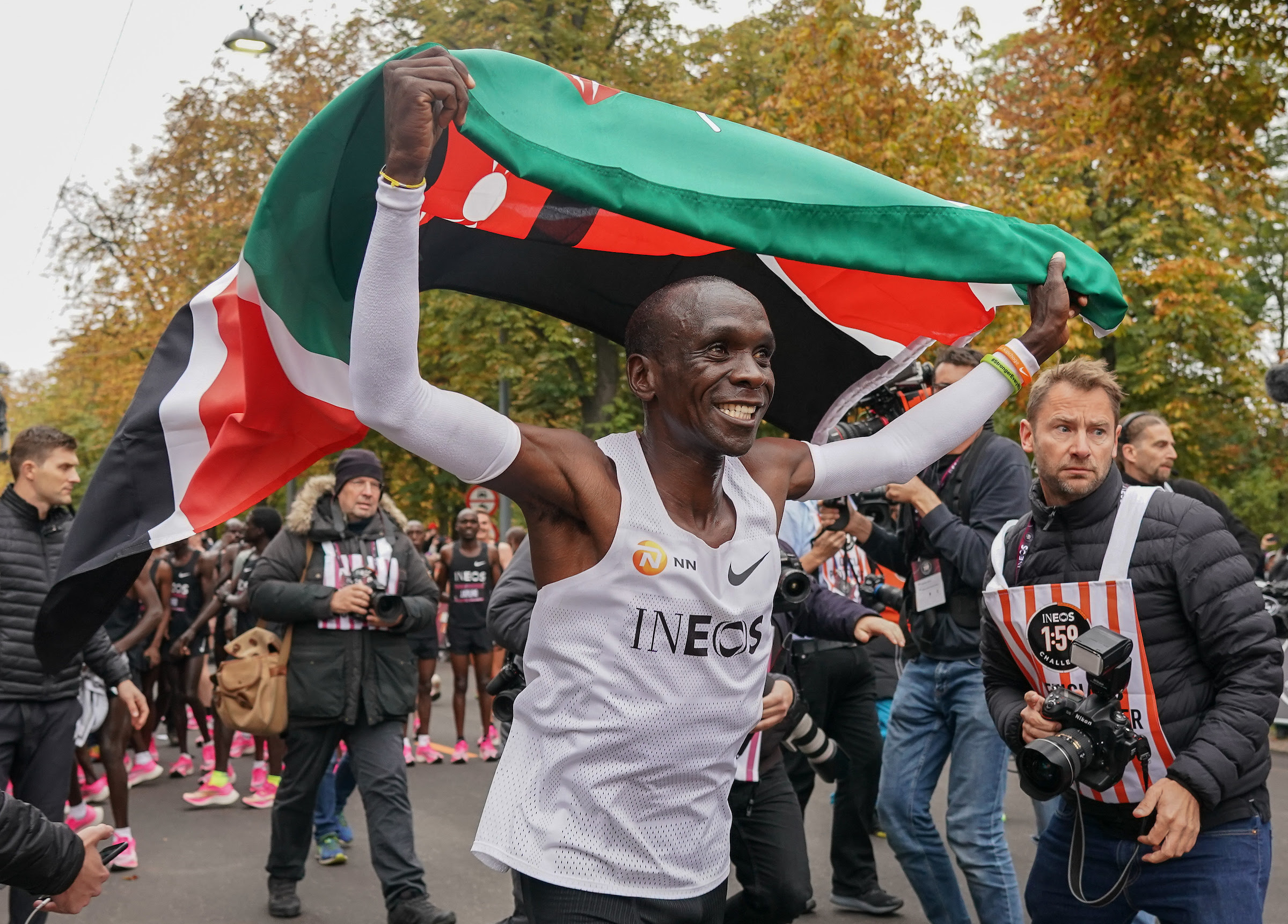 Free for editorial use and archive. Eliud Kipchoge celebrates with a Kenyan flag after crossing finish line to break the historic two hour barrier for a marathon. The INEOS 1:59 Challenge, Vienna, Austria. 12 October 2019. Photo: Jed Leicester for The INEOS 1:59 Challenge