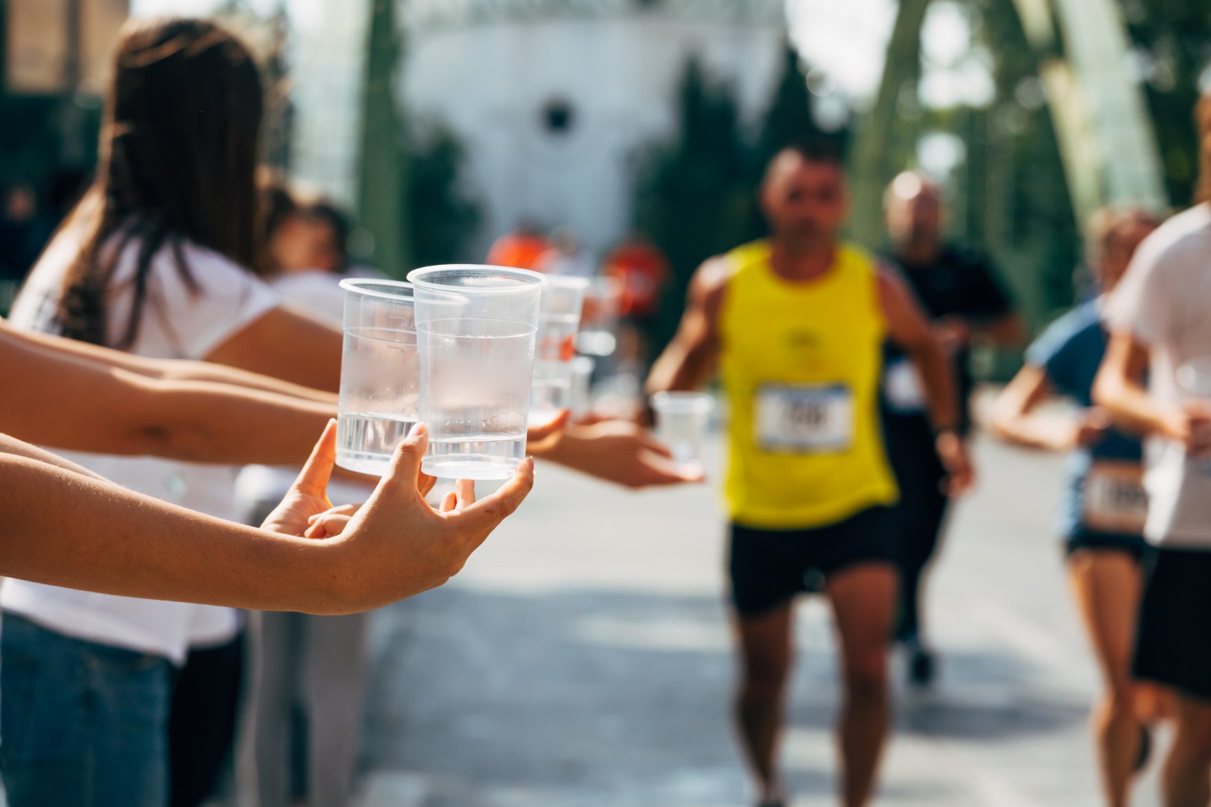 Marathoner taking water from volunteer